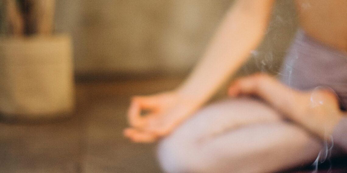 Woman sitting in lotus position meditating in forest clearing