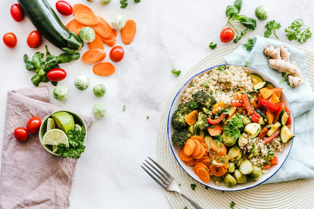 Wooden table with colorful vegetables and grains on plate