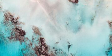 Woman standing peacefully in open green field with arms wide